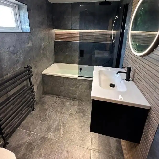 Dark contemporary bathroom with charcoal tiles, wood-slat feature wall, built-in tub and walk-in shower with black rainfall showerhead